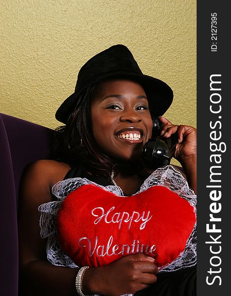 African american woman close up portrait talking on the phone with her boyfriend and holding happy valentine pillow. African american woman close up portrait talking on the phone with her boyfriend and holding happy valentine pillow