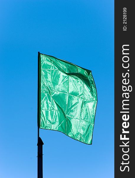 Green flag waving sky background