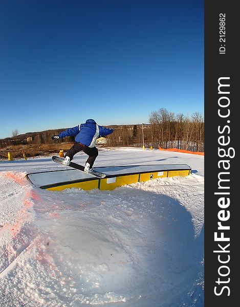 A snowboarder on a curved rail. A snowboarder on a curved rail