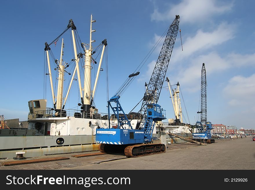 Two harbor cranes next to a ship.