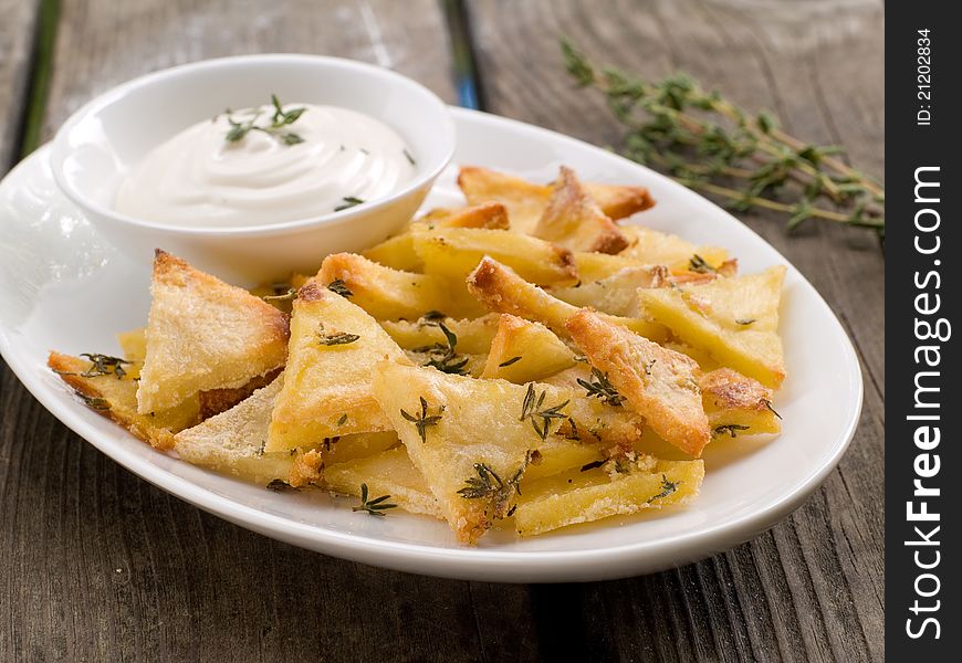 Roasted potatoes with bowl of sauce. Selective focus