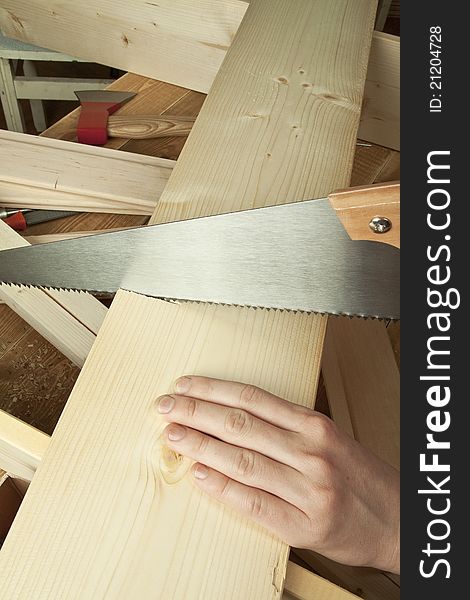 Man sawing plank on a wooden background.