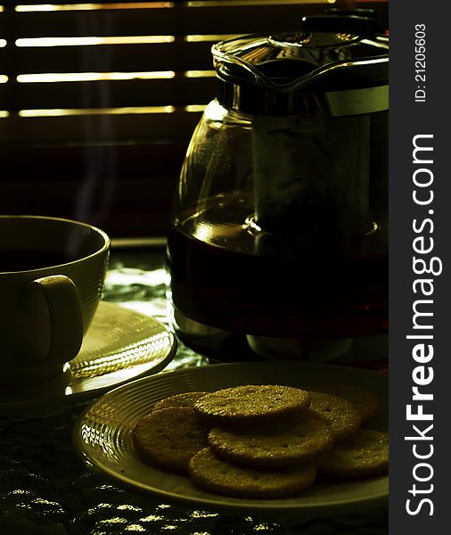 Smoking hot tea served with biscuits in a dramatic afternoon light. Smoking hot tea served with biscuits in a dramatic afternoon light.