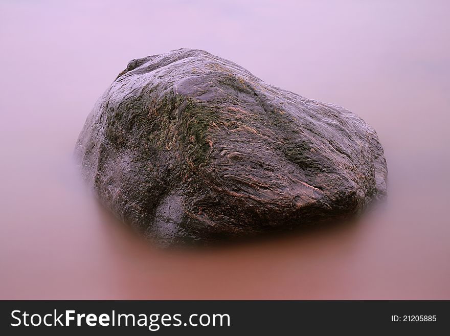 Abstract photo of large stone shot with long shutter speed to create misty effect in water. Abstract photo of large stone shot with long shutter speed to create misty effect in water