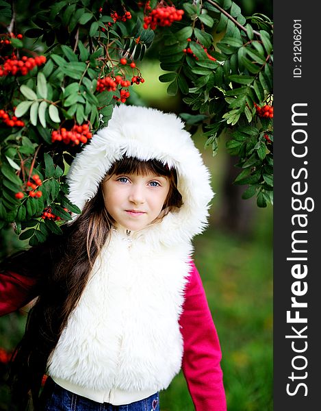 Cute Little Girl In Fur Coat Under Rowan Tree