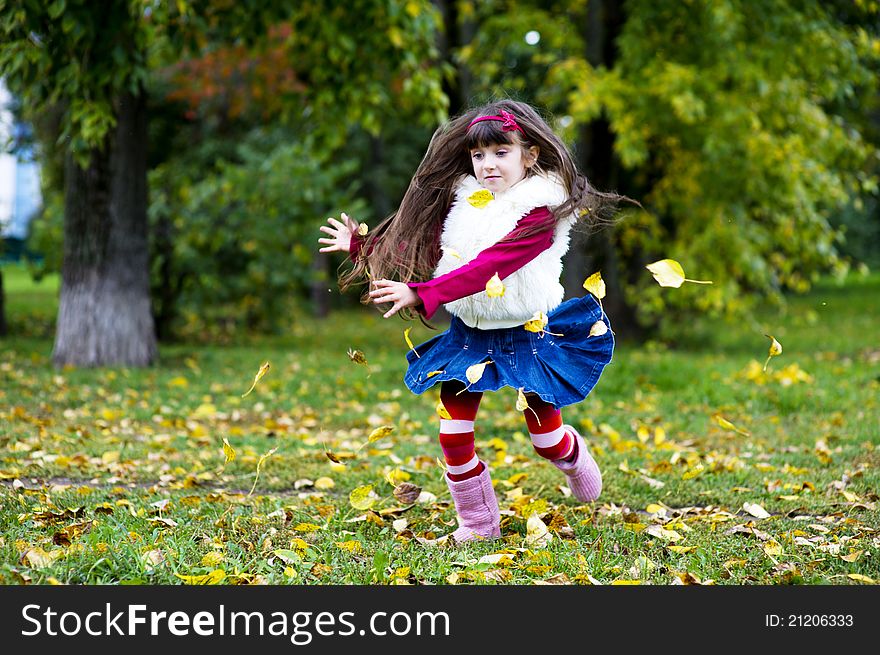 Adorable little brunette girl in pink outfit jumping with yellow leaves. Adorable little brunette girl in pink outfit jumping with yellow leaves