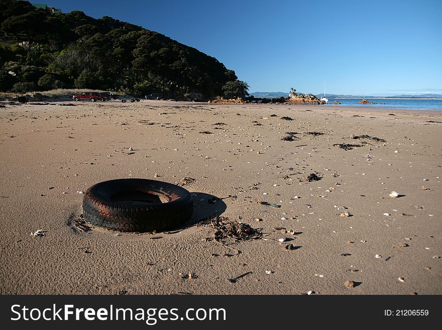 An abandoned tire sits on a quiet, sandy beach