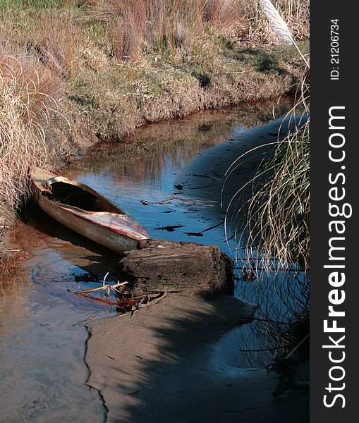 A derelict kayak sits in a tidal estuary. A derelict kayak sits in a tidal estuary