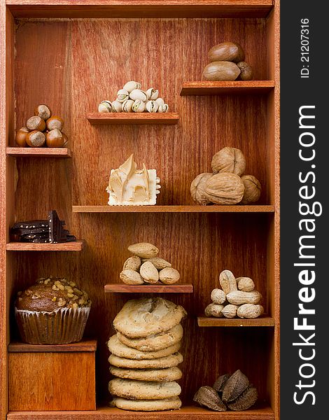 Assortment of different nuts and foods with nuts in them in a wooden shelf. Assortment of different nuts and foods with nuts in them in a wooden shelf.