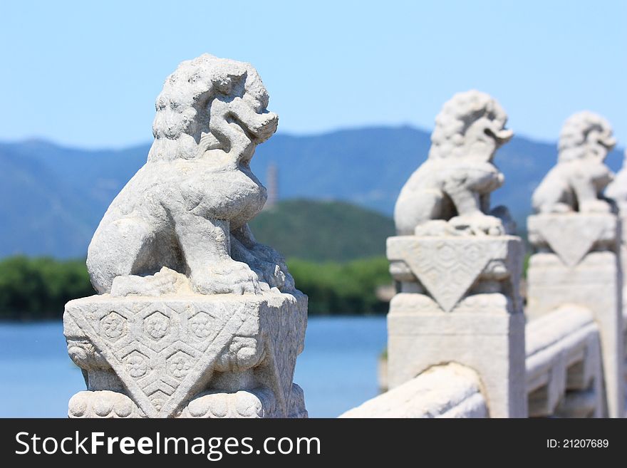 In the Summer Palace, these 544 carved white marble lions, in distinctive postures, sit at the column of the parapets on the 17-arch Bridge, which looks like a rainbow arching over the lake water.Beijing, China. In the Summer Palace, these 544 carved white marble lions, in distinctive postures, sit at the column of the parapets on the 17-arch Bridge, which looks like a rainbow arching over the lake water.Beijing, China