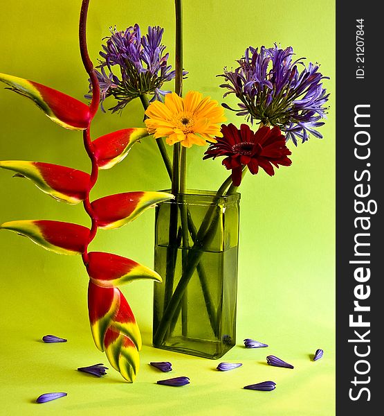 Assorted flowers in green vase on green background. Assorted flowers in green vase on green background