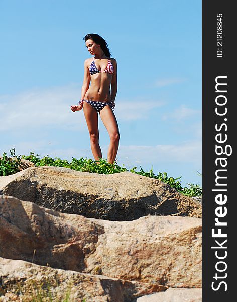 Beautiful brunette model standing on a rock. Beautiful brunette model standing on a rock.