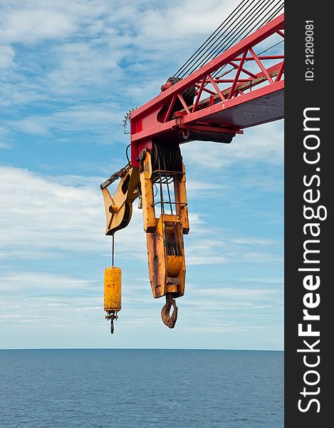 A boom of a crane on a semi-submersible drilling unit with a hook hovering over the horizon line. A boom of a crane on a semi-submersible drilling unit with a hook hovering over the horizon line.