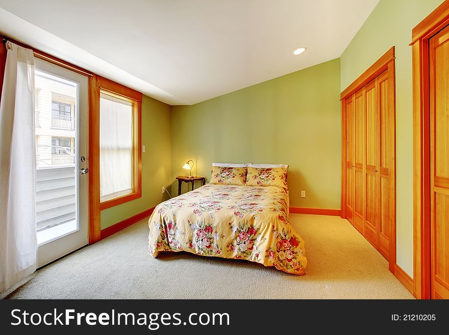 Large bright green bedroom with floral bedding and white curtains. Large bright green bedroom with floral bedding and white curtains.