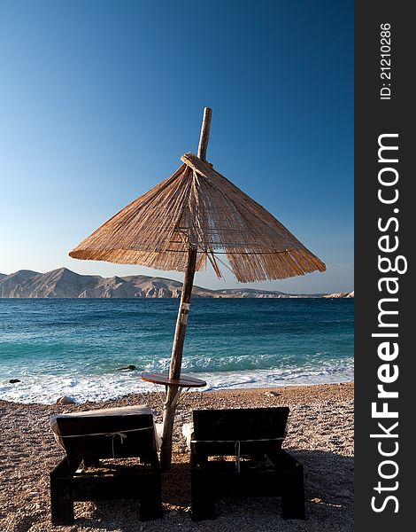 Two chairs and umbrella for relaxation on the pebble beach. (Baska - Krk - Croatia). Two chairs and umbrella for relaxation on the pebble beach. (Baska - Krk - Croatia)