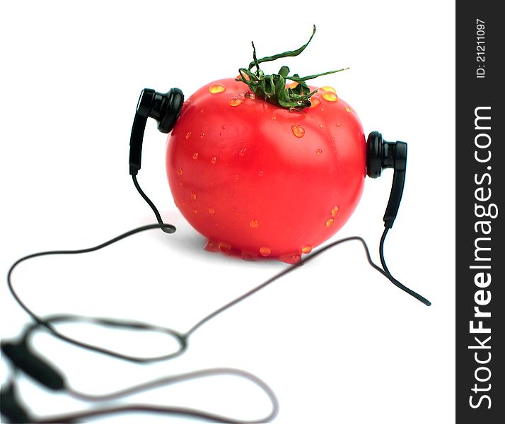 Red tomato in ear-phones on a white background. Red tomato in ear-phones on a white background