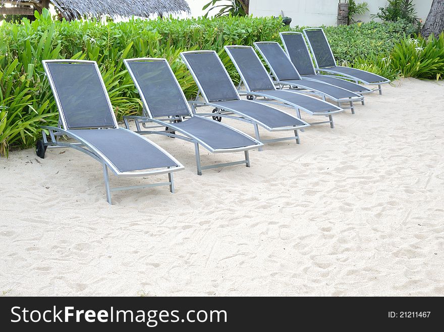 Row of blue beach chair on clear sand beach.