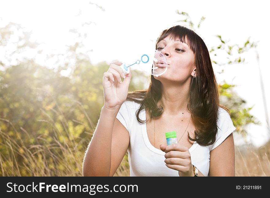 Young beautiful girl blowing bubbles