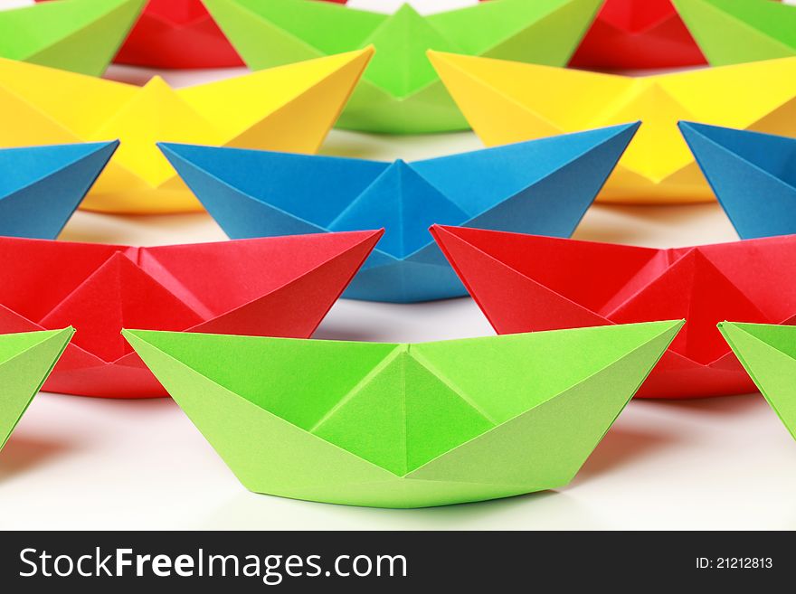 Several colored paper boats on white background