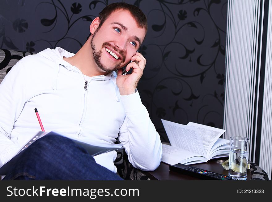 Young and attractive guy calling by phone and write something in notebook. Young and attractive guy calling by phone and write something in notebook