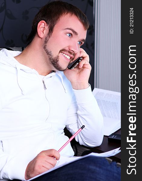 Young and attractive guy calling by phone and write something in notebook. Young and attractive guy calling by phone and write something in notebook