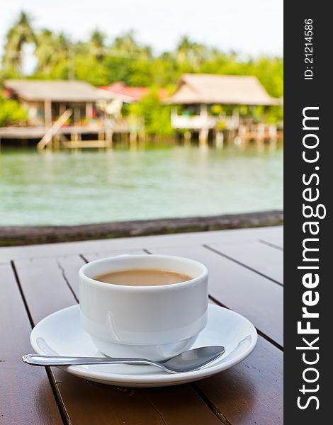 A cup of coffee on wood table with river view. A cup of coffee on wood table with river view