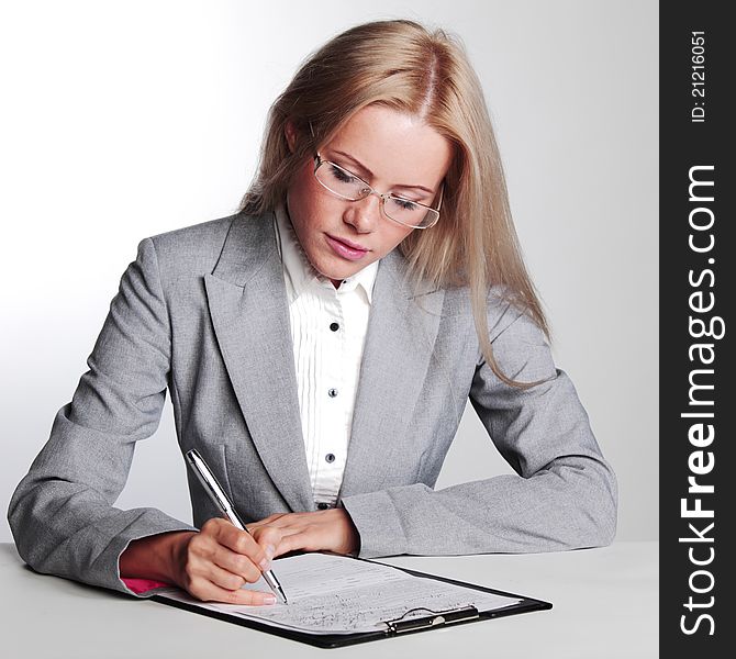 Business woman writing in notebook on a gray background