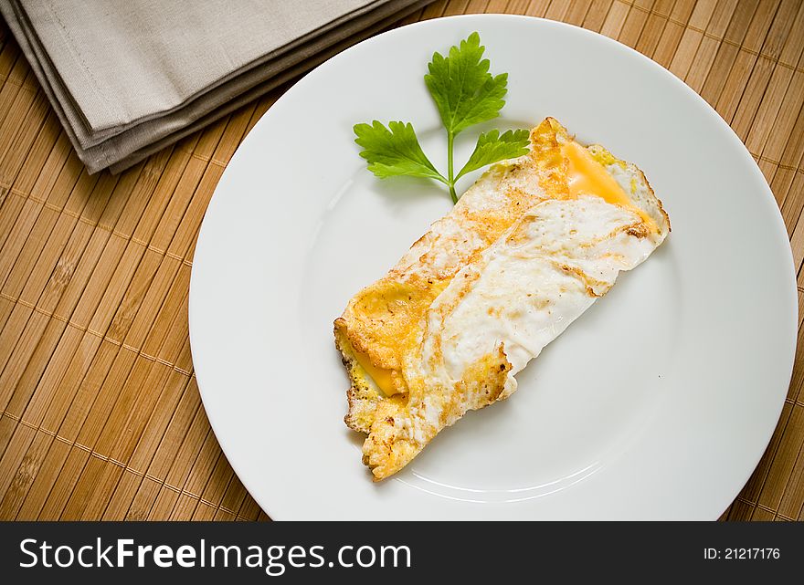 A plate of eggs Omelet with cheese in a white plate and light brown background. A plate of eggs Omelet with cheese in a white plate and light brown background.