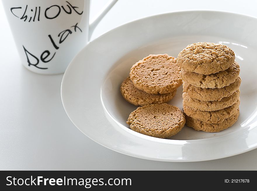 Cookies in a white plate and a cup of milk in a white background. Cookies in a white plate and a cup of milk in a white background