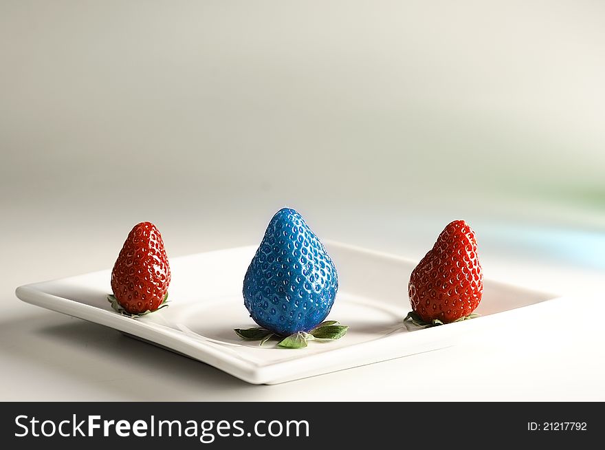 A genetically modified blue strawberry bigger and different from the rest. Concept for genetically modify food. A genetically modified blue strawberry bigger and different from the rest. Concept for genetically modify food.