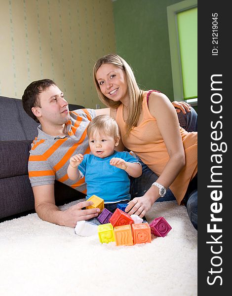 Family with baby boy sitting on floor at home and playing together. Family with baby boy sitting on floor at home and playing together.