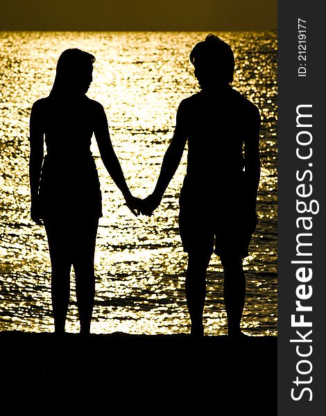 The shot of Couple standing on the beach, holding hand and look to each other. The shot of Couple standing on the beach, holding hand and look to each other.