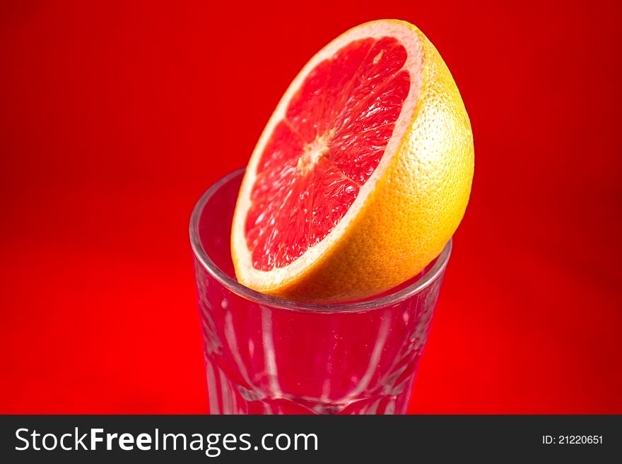 A half grapefruit lying on top of a glass. A half grapefruit lying on top of a glass