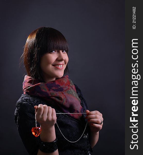 Young beautiful woman holding heart, on dark background