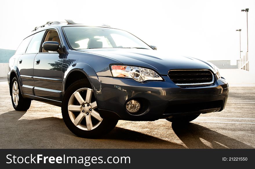 Front and side view of blue wagon on parking lot, backlit. Front and side view of blue wagon on parking lot, backlit