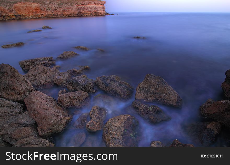 The sea stones scattered in picturesque disorder largely on seacoast with become blue water. The sea stones scattered in picturesque disorder largely on seacoast with become blue water