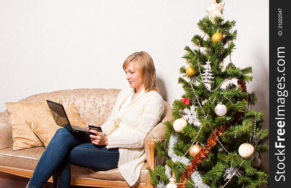 A young woman sits with a notebook near a new-year tree. A young woman sits with a notebook near a new-year tree