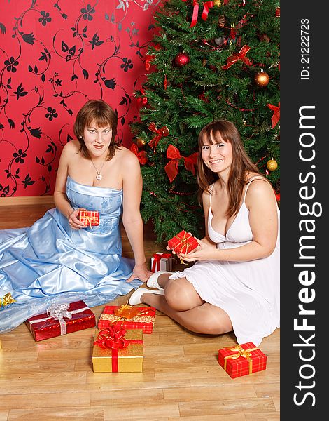 Two young women with gifts near a new-year tree. Two young women with gifts near a new-year tree