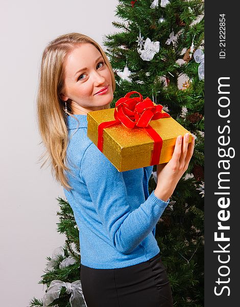 Young woman with a gift near a new-year tree. Young woman with a gift near a new-year tree