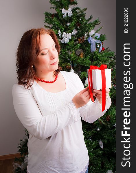 Mid adult woman with a gift near a new-year tree. Mid adult woman with a gift near a new-year tree