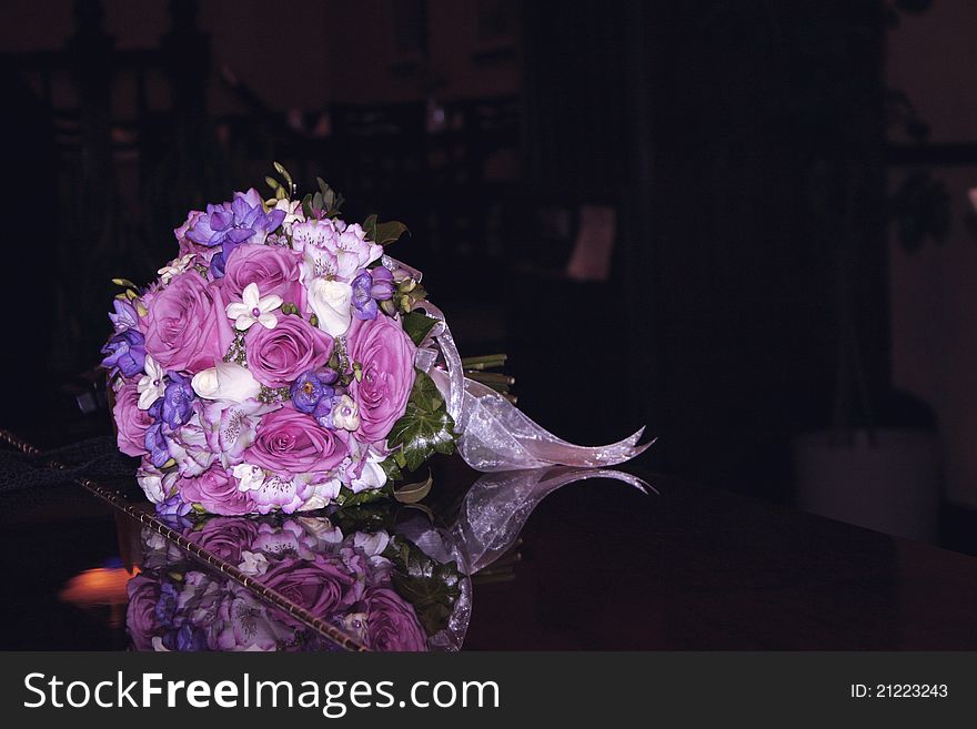 A bride's bouquet of purple, pink and white flowers tied with ribbon set down on a shiny black piano. A bride's bouquet of purple, pink and white flowers tied with ribbon set down on a shiny black piano.