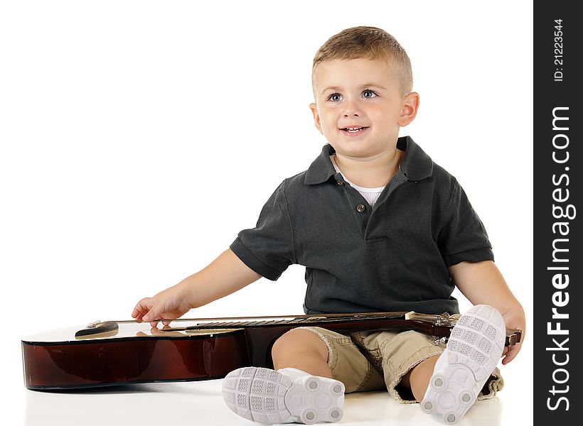 An a dorable toddler looking up as he plucks the strings of a classic guiatar. Isolated on white. An a dorable toddler looking up as he plucks the strings of a classic guiatar. Isolated on white.