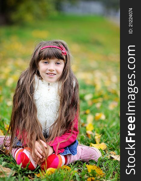 Cute little girl wearing fur coat in autumn forest