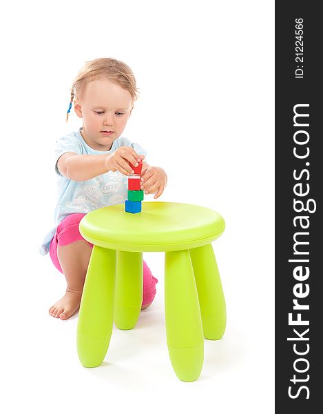 Little girl puts on a stool colorful wooden blocks. Little girl puts on a stool colorful wooden blocks