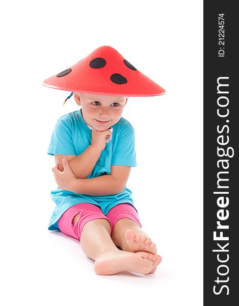 Little girl sitting in studio in funny red hat on her head. Little girl sitting in studio in funny red hat on her head