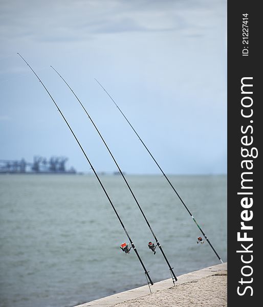 Three spinning rods on the coast of ocean. Lisboa, Portugal