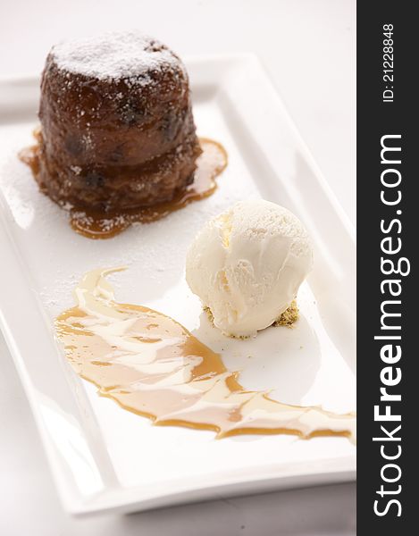 Sticky date pudding with vanilla ice cream and caramel sauce served on a plate. Sticky date pudding with vanilla ice cream and caramel sauce served on a plate
