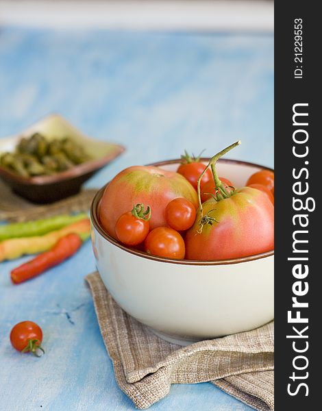 Organic vegetables in a bowl, on a blue wooden surface, tomatoes