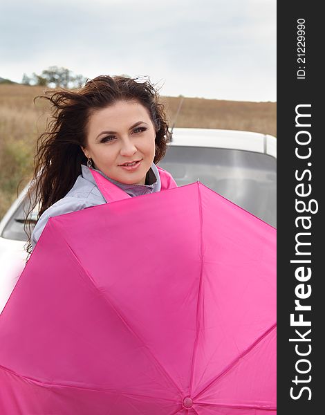 Beautiful lady with bright pink umbrella standing near her car. Beautiful lady with bright pink umbrella standing near her car