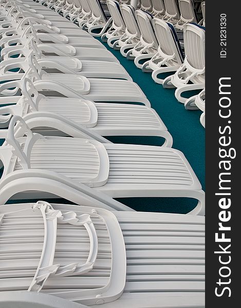 Row of folded white beach chairs not in use.